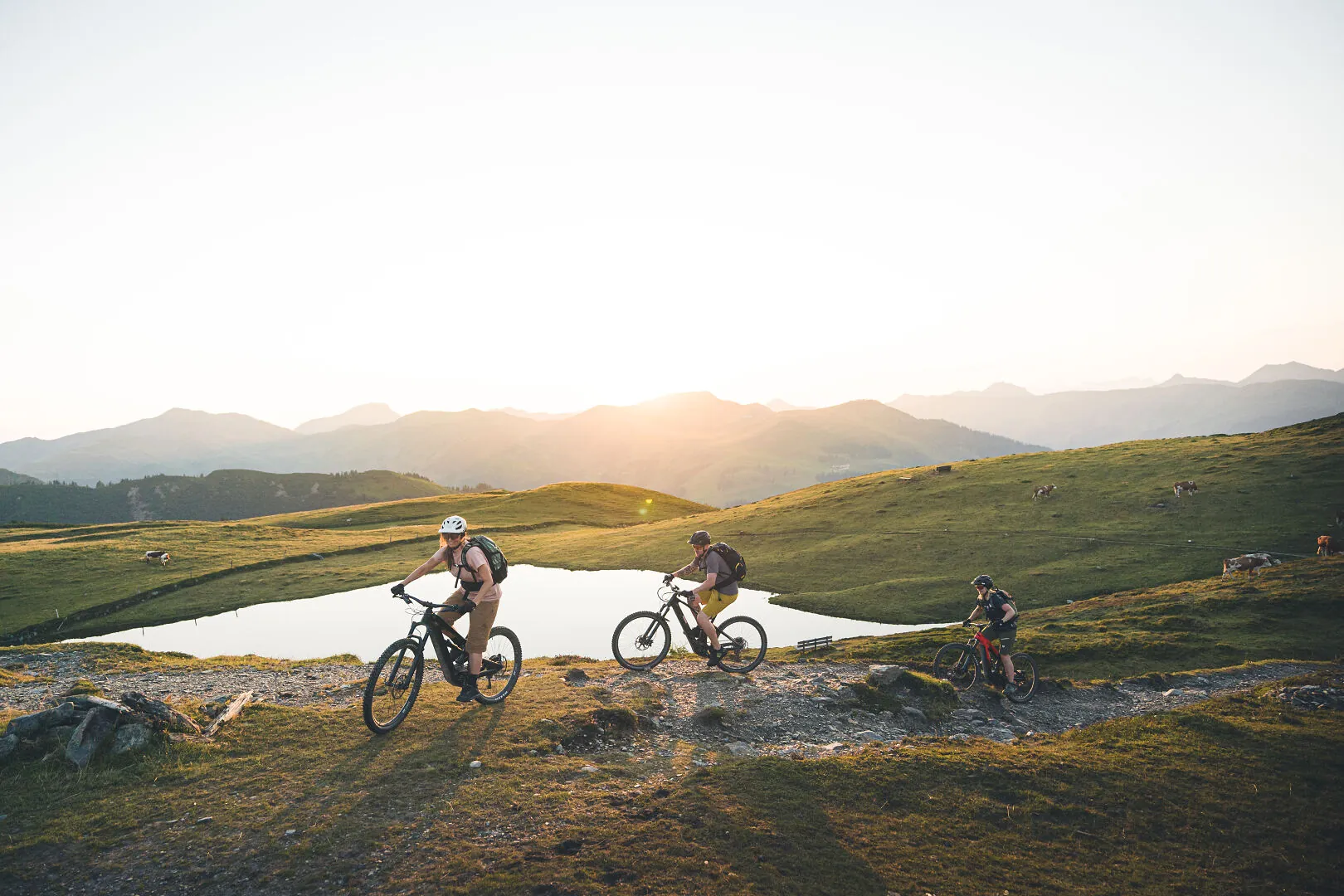 Mountainbikers bij een bergmeertje in het licht van de ondergaande zon
