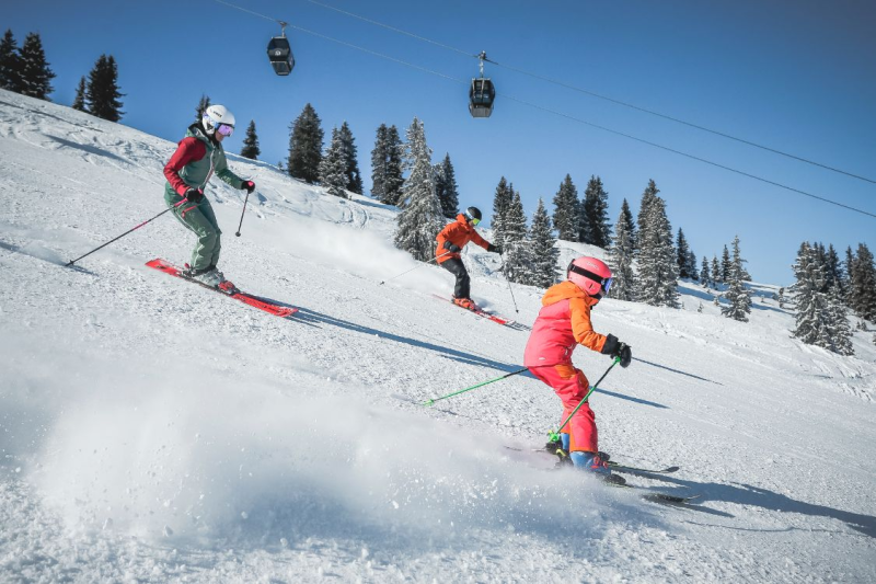 Familie skiet samen op de piste in Fieberbrunn