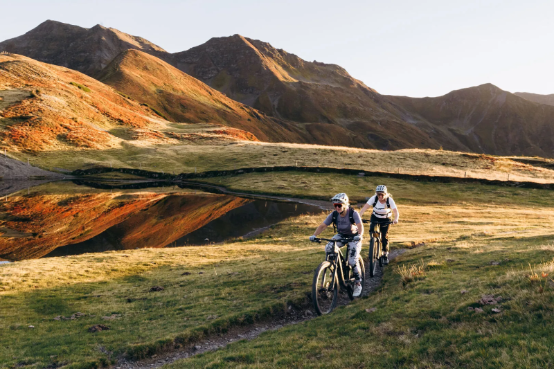 Twee fietsers op een bergpad langs een bergmeertje