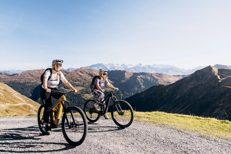 Twee e-bikers op een bergweg met uitzicht op de bergen