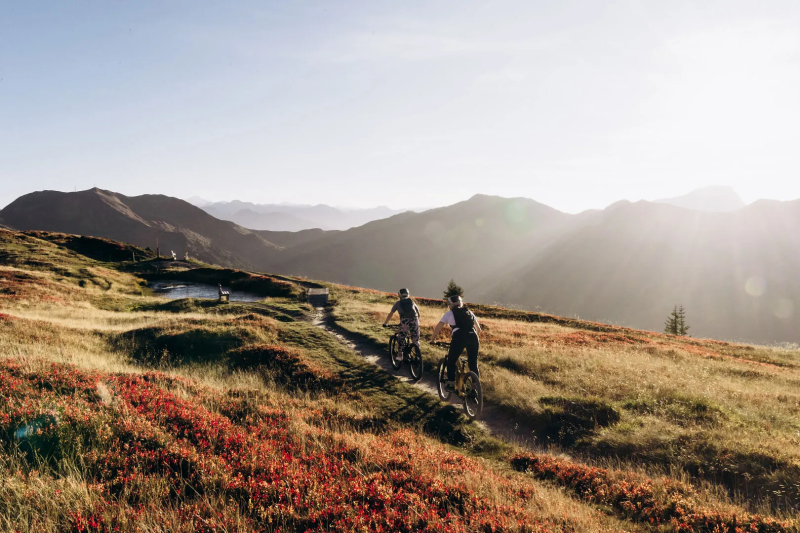 Mountainbikers op een bergflank met rode herfstkleuren