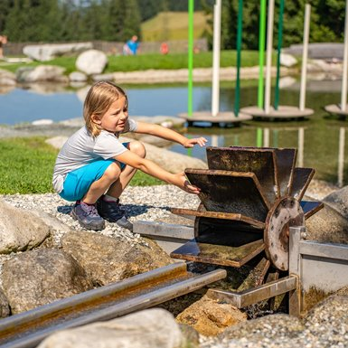 Kind speelt in de waterwelt van Timoks Wilde Welt in Fieberbrunn