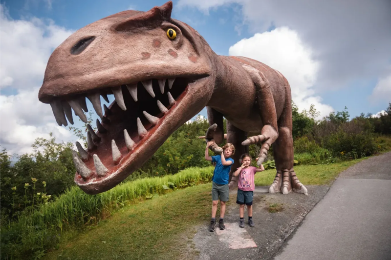 Met het gezin wandelen in de Dinosaurusbeeld langs het wandelpad met het gezin in Fieberbrunnbergen bij Fieberbrunn