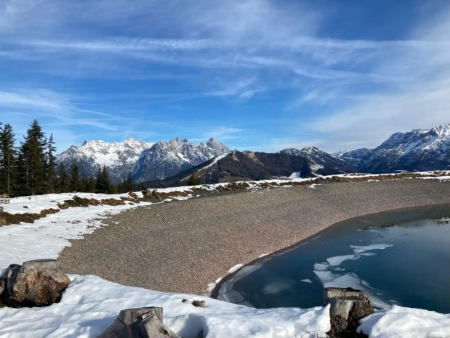 Stuwmeer op de bergkam met sneeuwresten langs de oever en besneeuwde toppen erachter – Rondje om de Streubödensee, Fieberbrunn