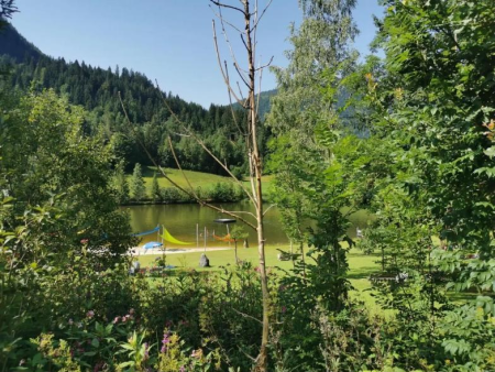 Uitzicht door bomen op het meer met ligweide – Lauchsee en Plezenbach – grote lus, Fieberbrunn
