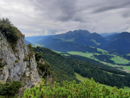 Metalen topkruis tussen sparren op een beboste top – Overtocht Buchensteinwand vanuit Hochfilzen, Fieberbrunn